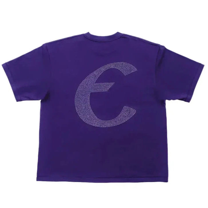 A purple short-sleeve t-shirt shown from the back, featuring a large, stylized letter 'C' outlined with a dense pattern of small silver rhinestones or studs.