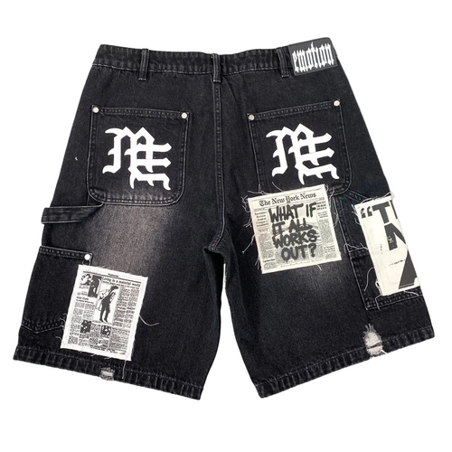 Black washed denim cargo shorts with multiple graphic patches and white gothic lettering on the back pockets, shown flat on a white background.